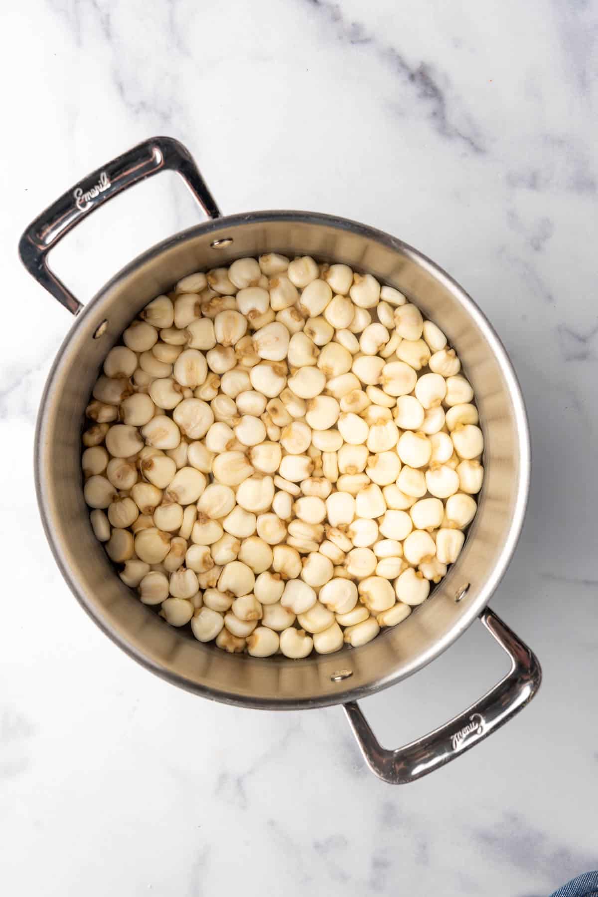 Dried hominy soaking in water in a large pot.