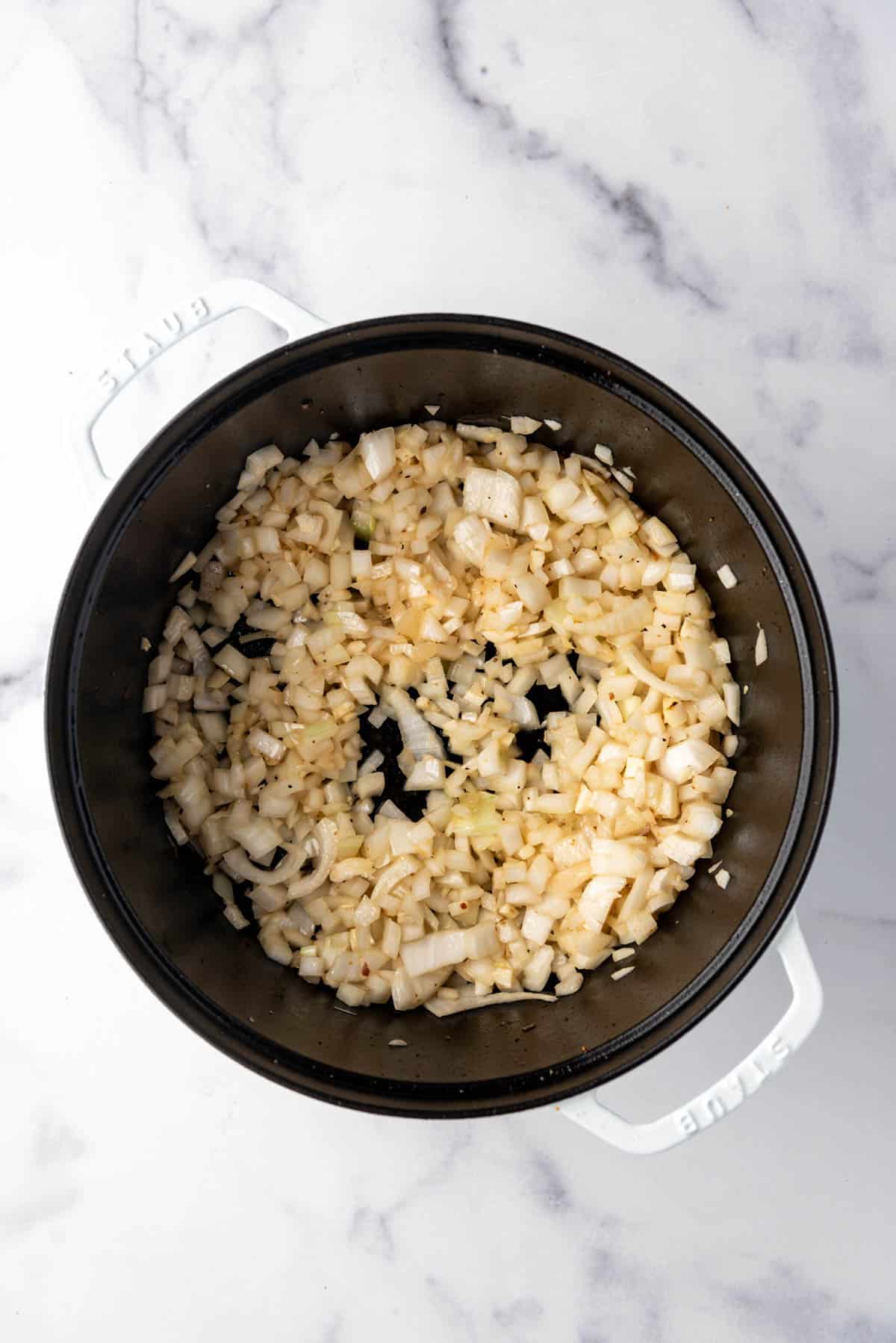 Sauteeing diced onions and garlic in a large dutch oven.