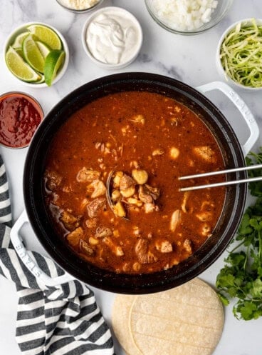 An overhead image of a large dutch oven pot filled with red New Mexico posole.