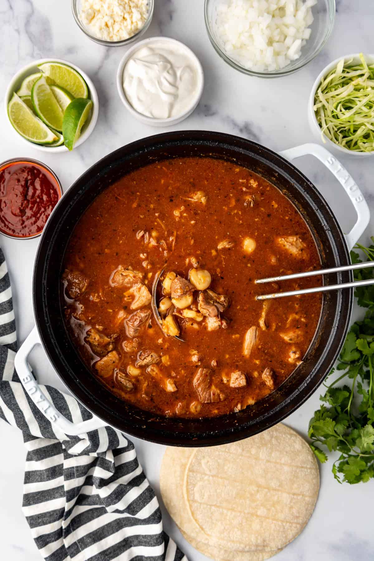 An overhead image of a large dutch oven pot filled with red New Mexico posole.