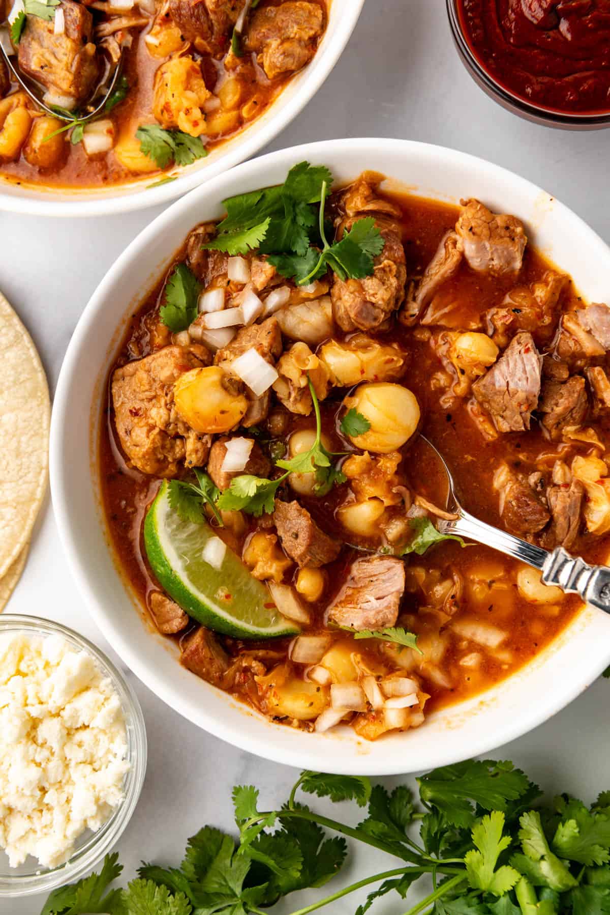 A bowl of posole with toppings.