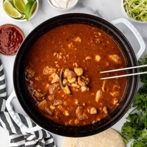 An overhead image of a large dutch oven pot filled with red New Mexico posole.