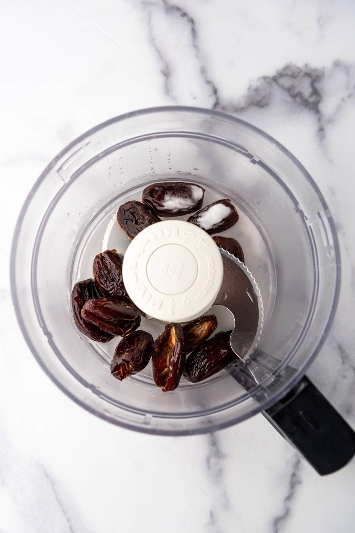 Adding dates, water, and baking soda to a food processor.