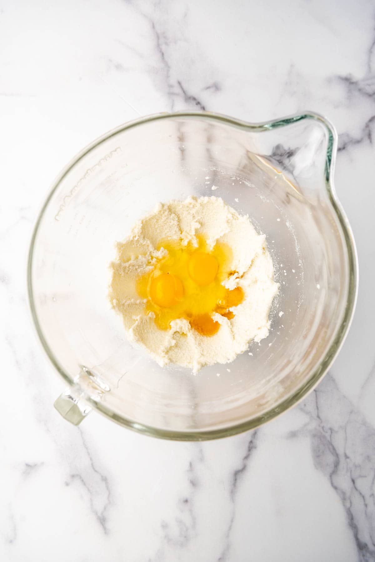 Adding eggs to creamed butter and sugar in a large mixing bowl.