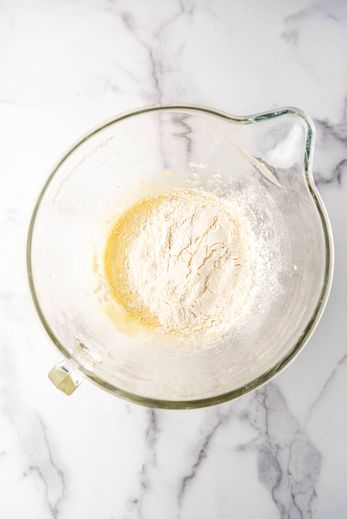 Adding dry ingredients to creamed wet ingredients in a large mixing bowl.