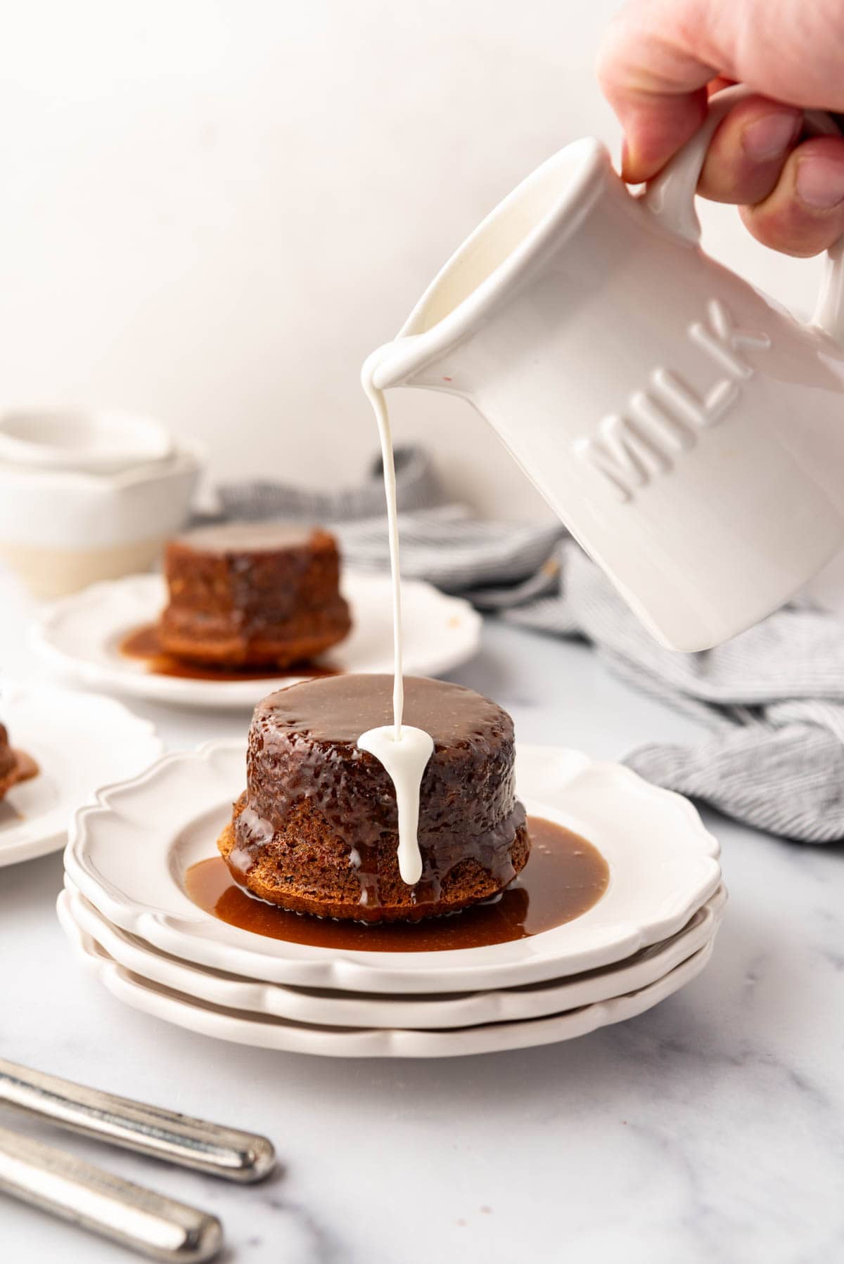 Pouring heavy cream onto sticky toffee pudding.