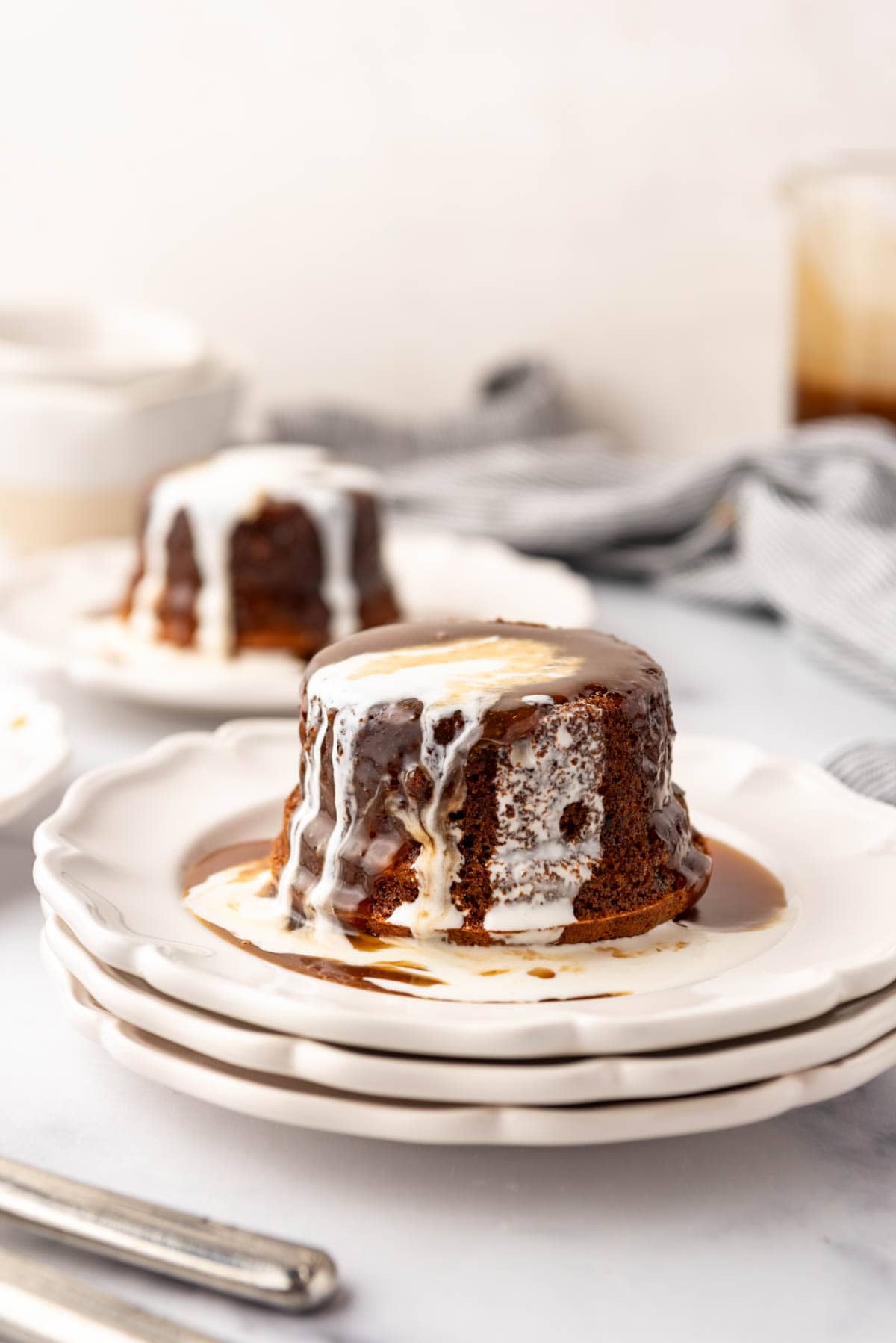 Plates of sticky toffee pudding with toffee sauce and cream poured on top.