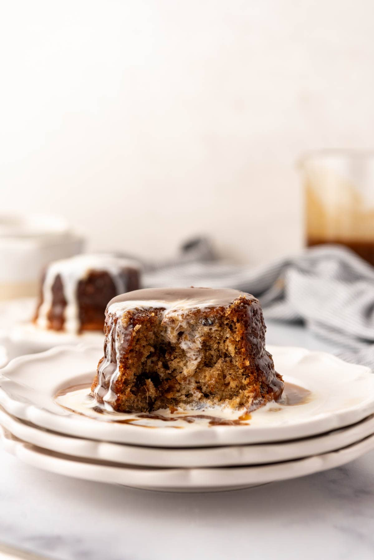 A plate of sticky toffee pudding with a bite taken out of it.