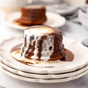 Plates of sticky toffee pudding with toffee sauce and cream poured on top.