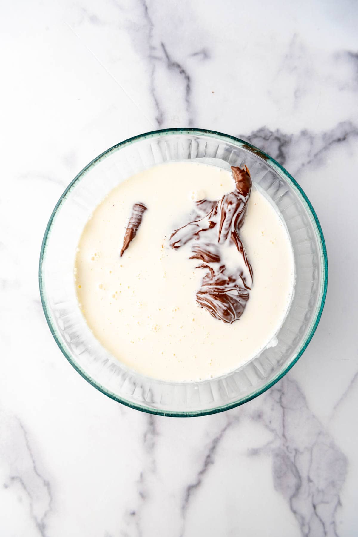 Adding Nutella to heavy cream and chocolate chips in a large mixing bowl.