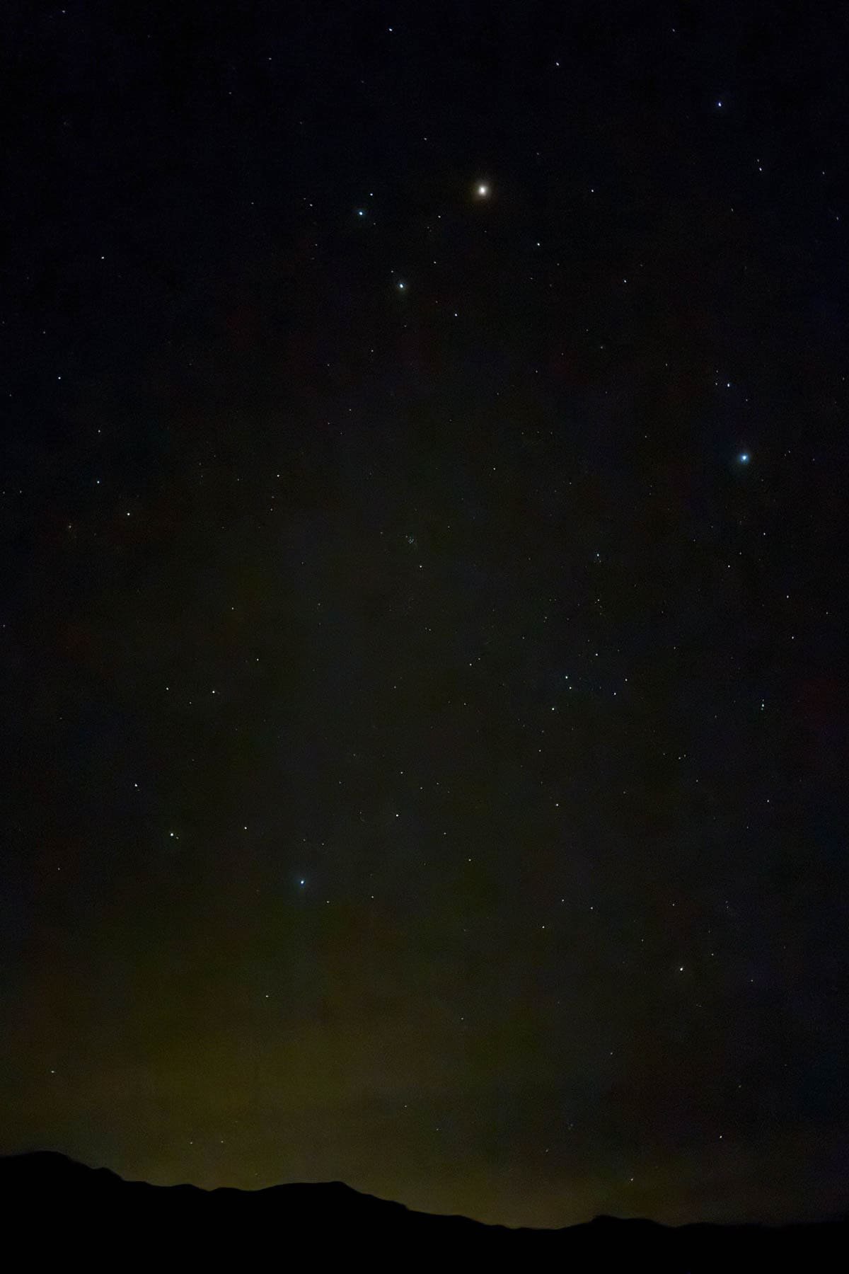 An image of the night sky with mountains in the foreground.