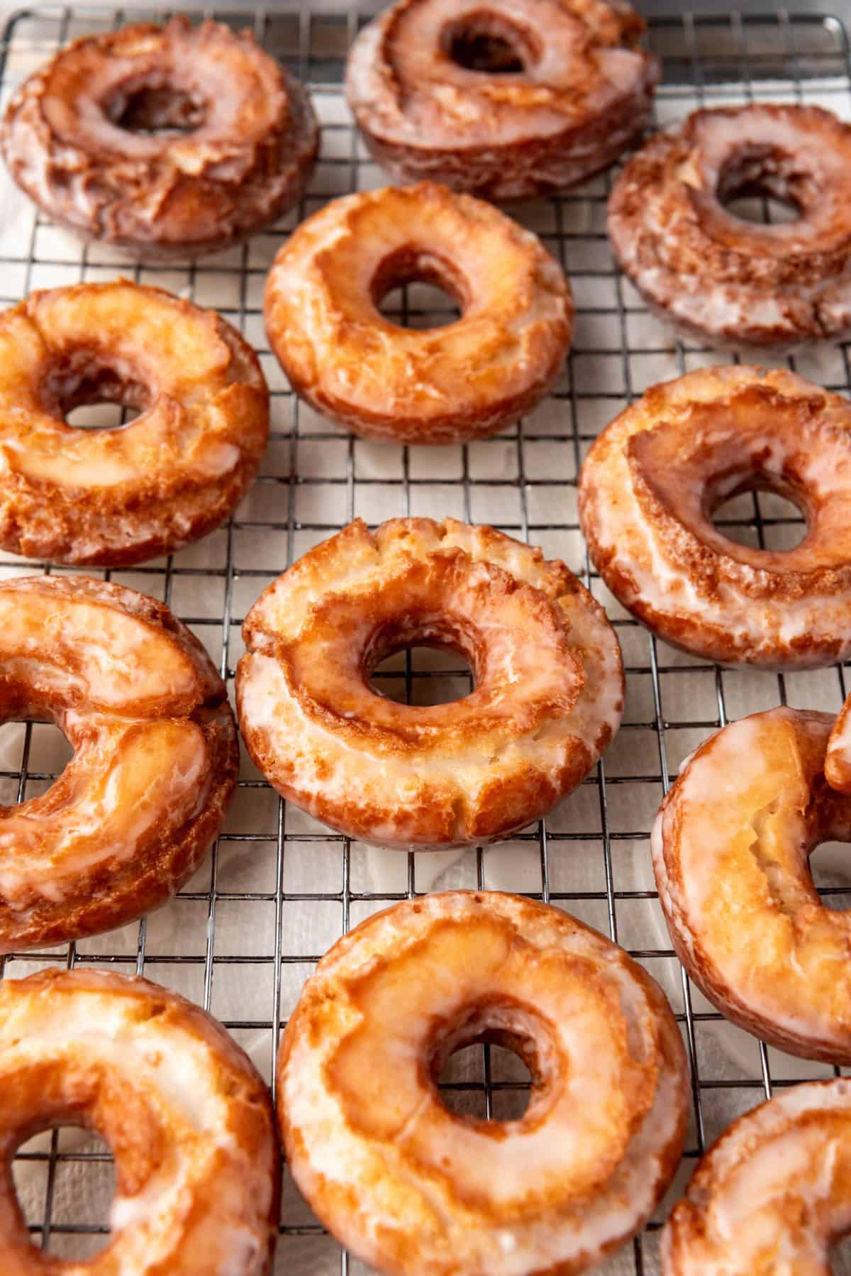 Old-fashioned doughnuts with craggy tops on a wire rack.