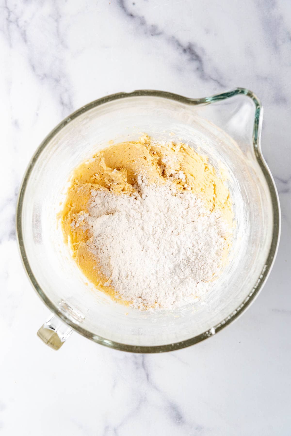 Adding dry ingredients to wet ingredients in a large mixing bowl.