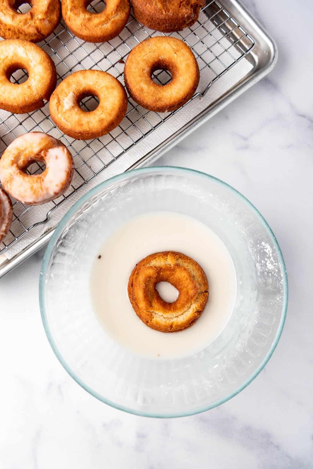 An image of a donut being dipped into a simple glaze.