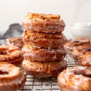 An image of glazed cake doughnuts staked on top of each other.