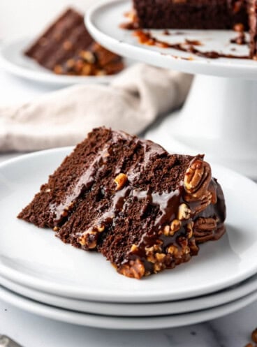 A slice of chocolate caramel turtle cake on a white plate.