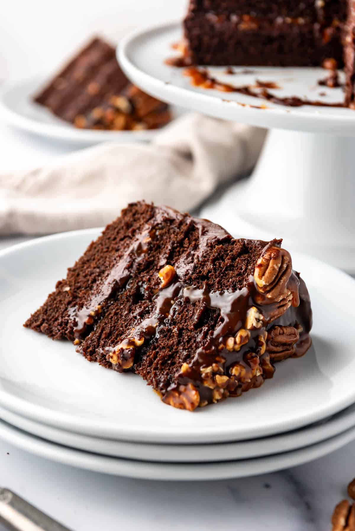 A slice of chocolate caramel turtle cake on a white plate.