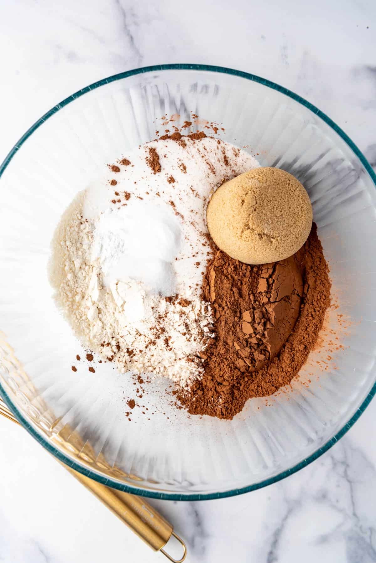 Combining flour, cocoa powder, and two types of sugar in a mixing bowl.