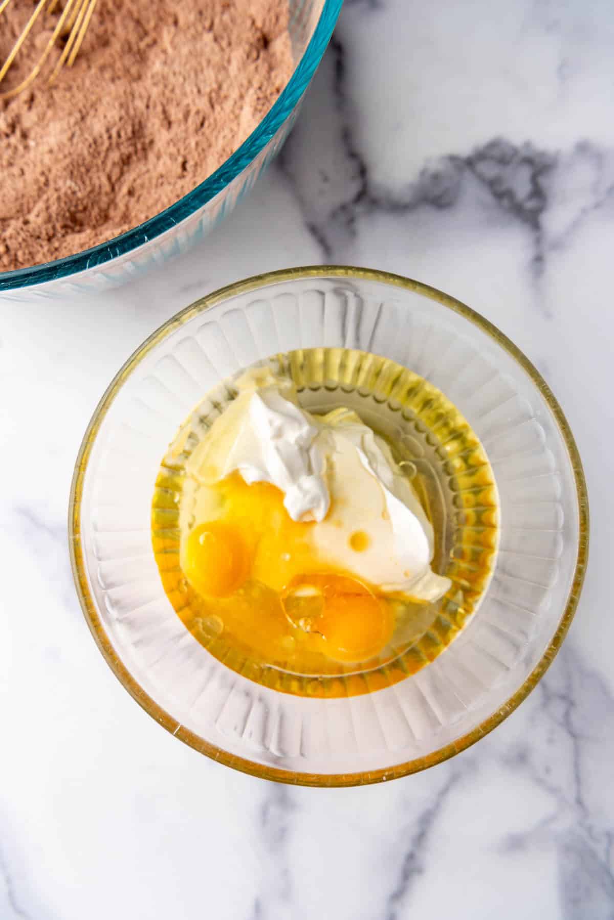 Combining eggs, oil, and sour cream in a mixing bowl.