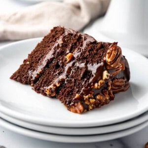 A slice of chocolate caramel turtle cake on a white plate.