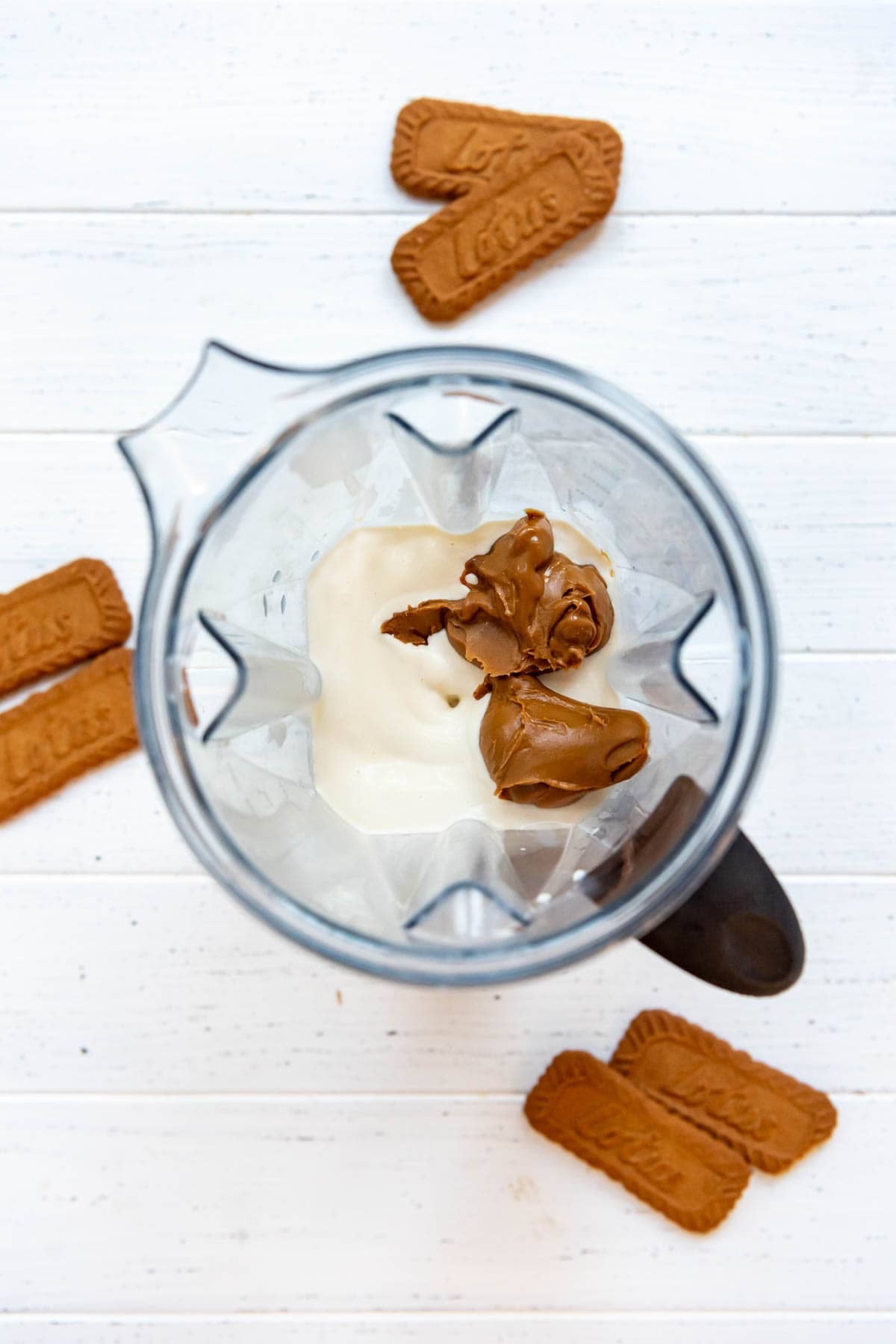 Adding cookie butter to milkshake mixture in a blender.