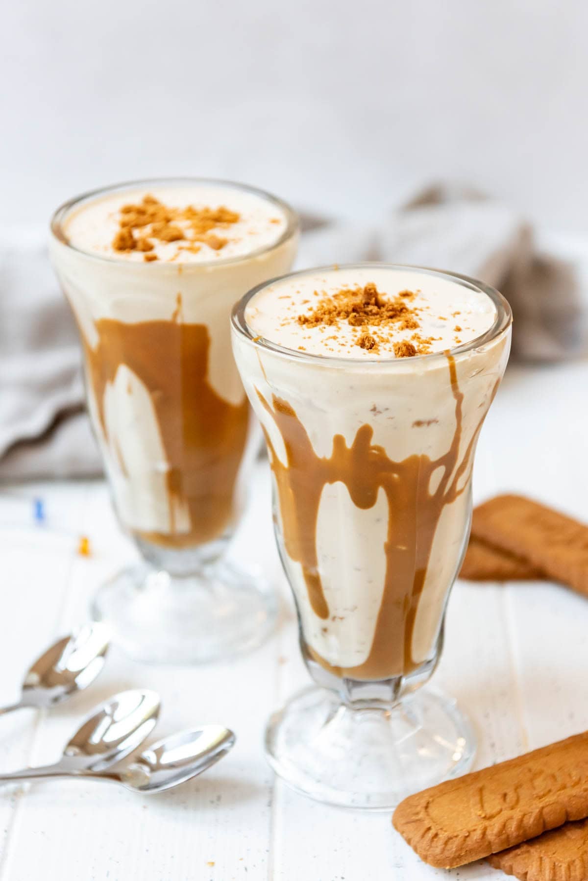Two Biscoff cookie butter milkshakes in tall white glasses.