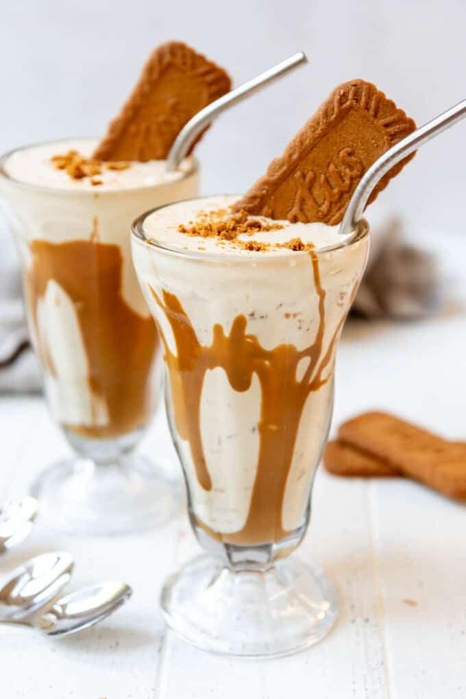 Tall milkshake glasses with cookie butter milkshake in them.