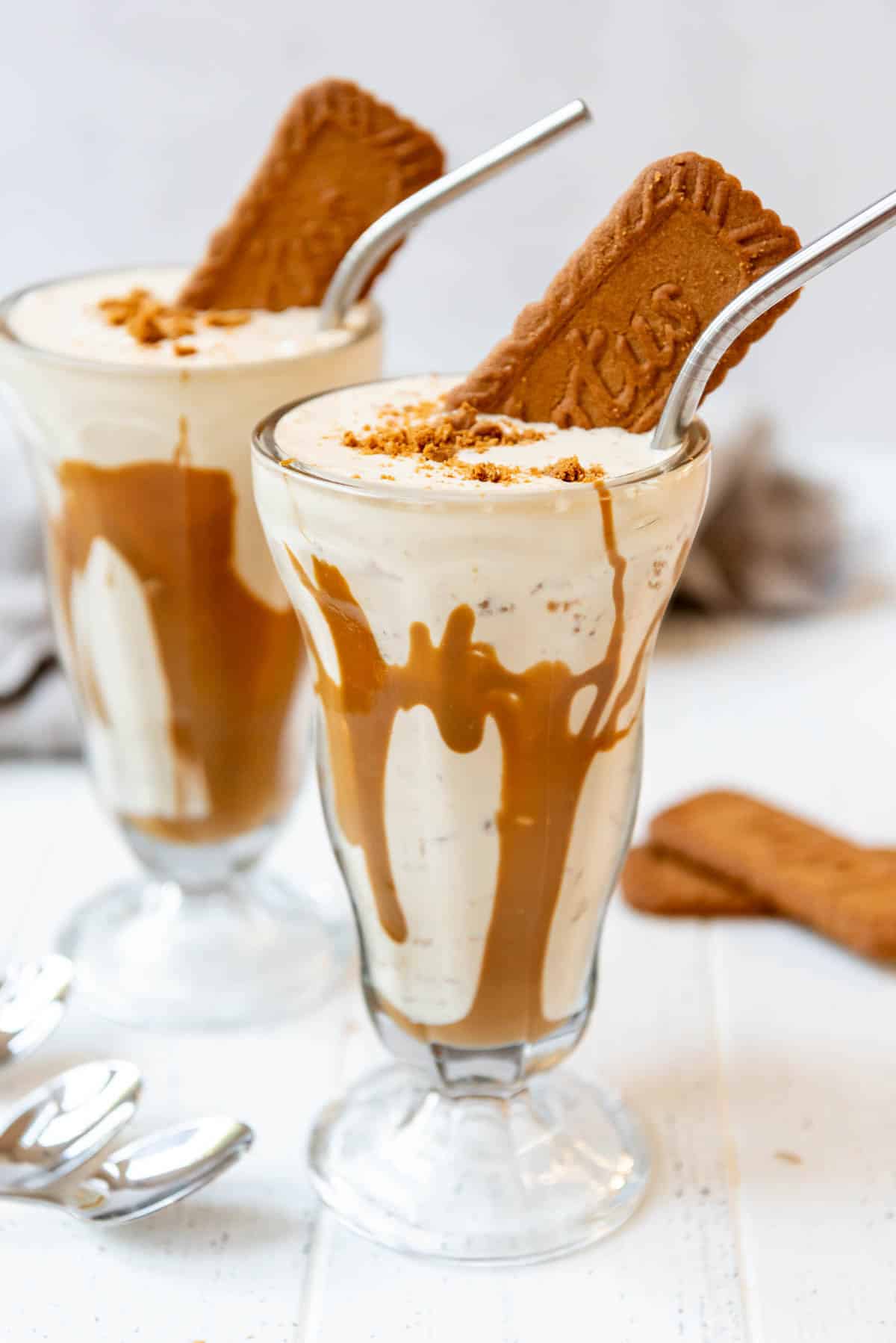 Tall milkshake glasses with cookie butter milkshake in them.