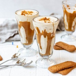 An image of two cookie butter milkshakes in glass milkshake glasses.