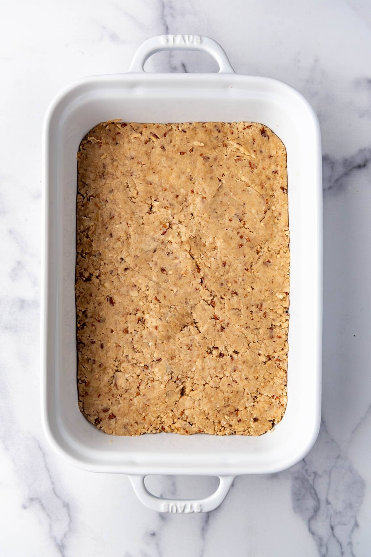 A pecan crust layer in a baking dish.