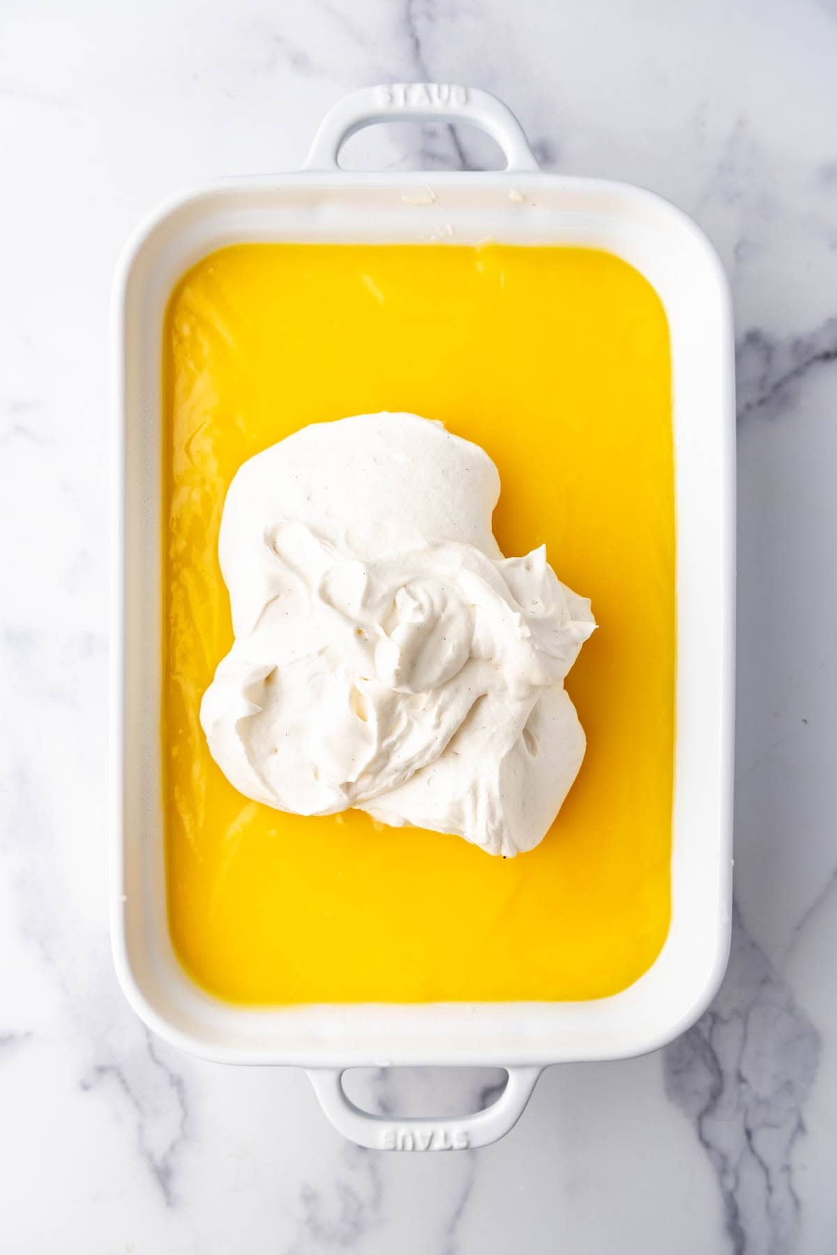 Adding a whipped cream layer over lemon pudding.
