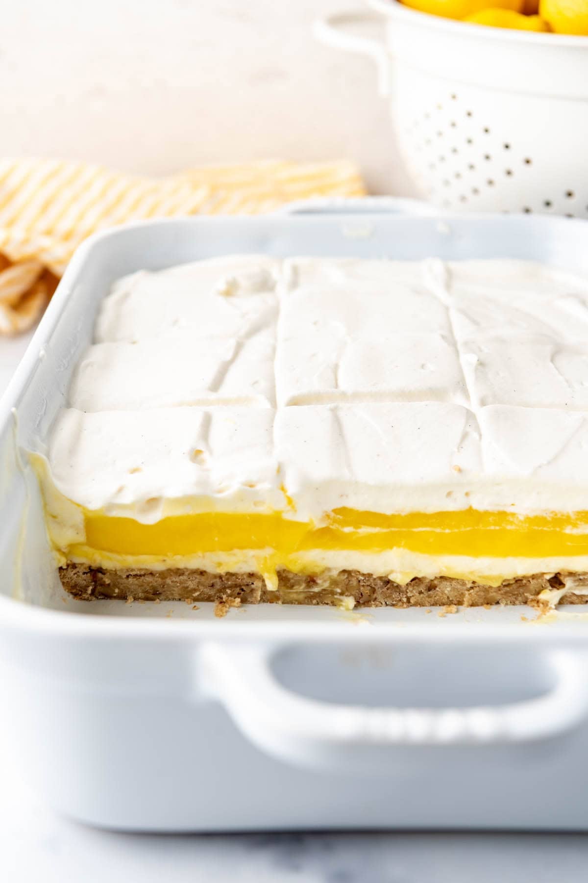 A close up image of a pan of lemon lush with slices removed so you can see the layers.