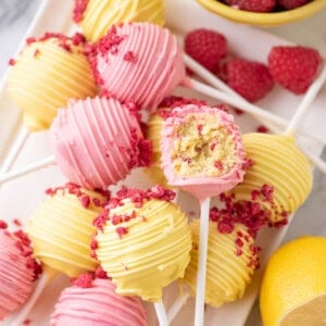 Lemon raspberry cake pops with a bite taken out of one of them.
