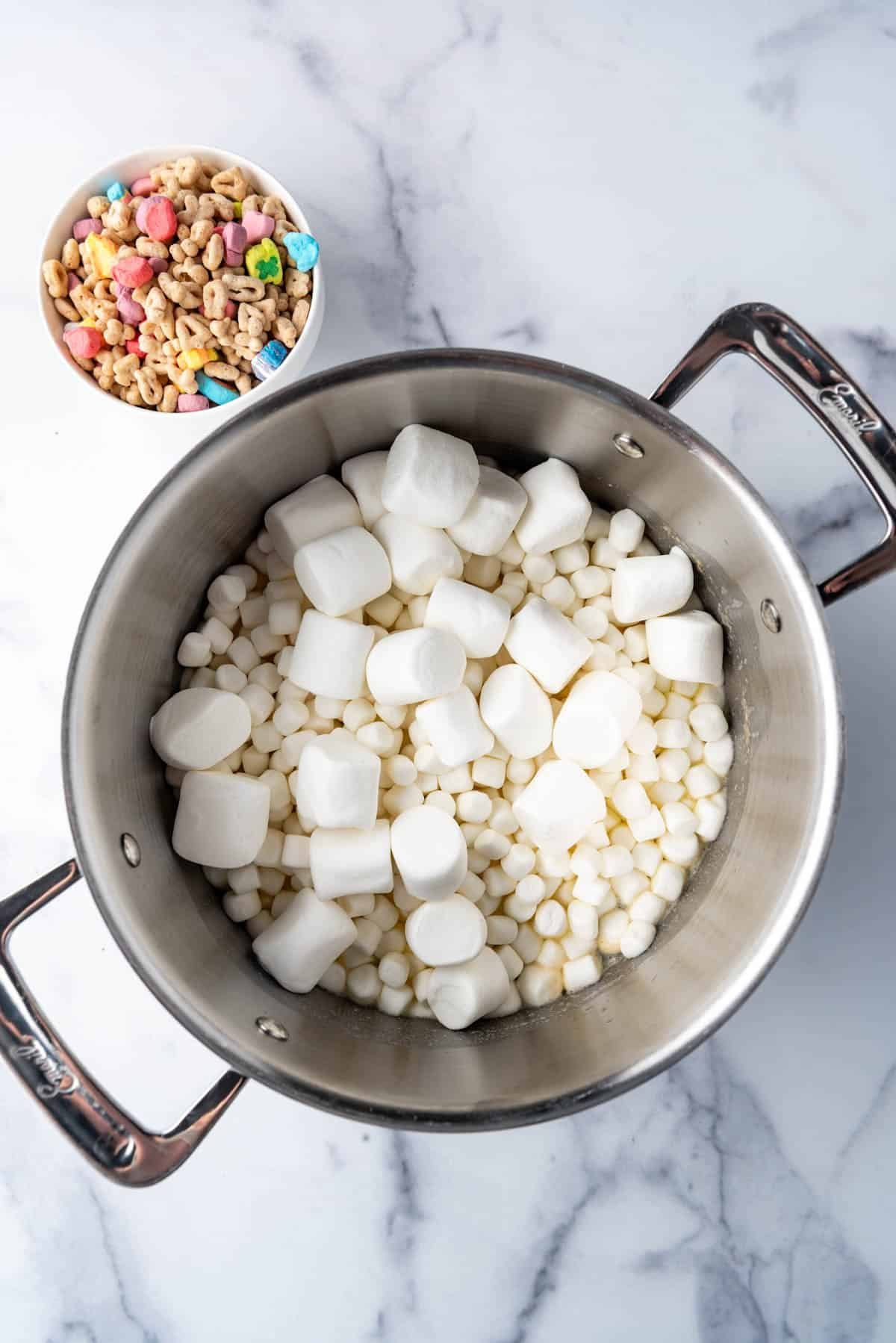 Combining marshmallows and melted butter in a large pot.