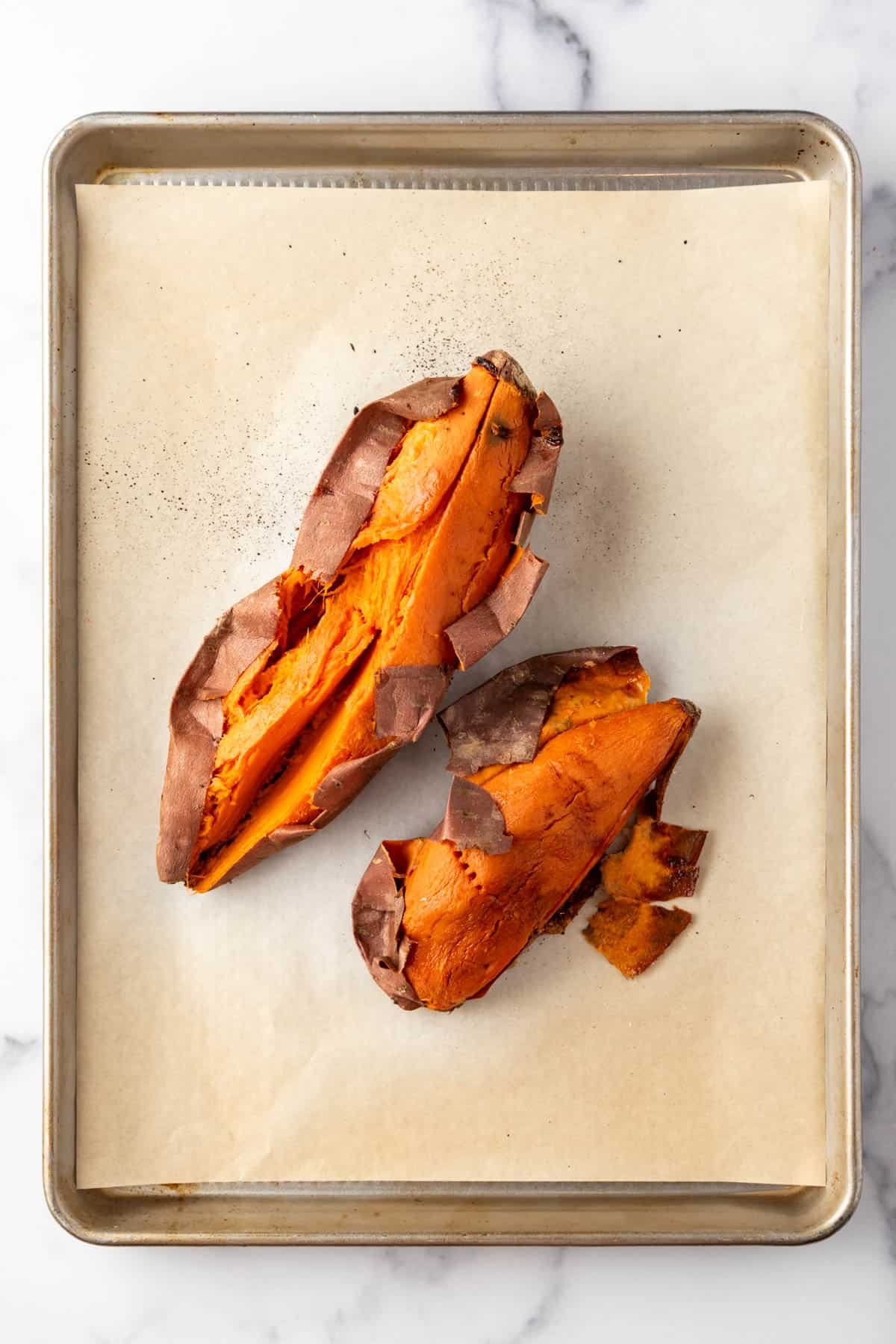 Roasted sweet potatoes on a baking sheet lined with parchment paper.