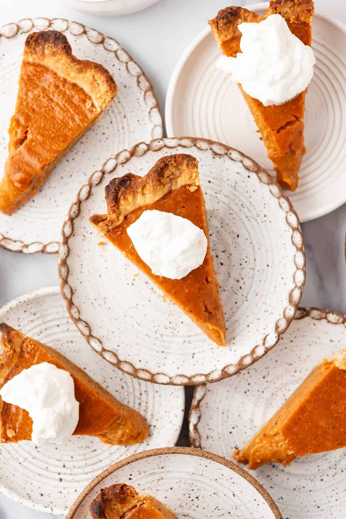 An overhead image of slices of sweet potato pie on overlapping plates.