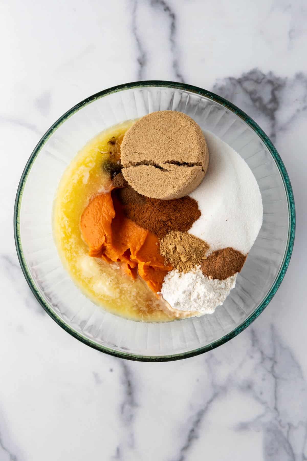 Combining sugar, spices, melted butter, and sweet potato puree in a large mixing bowl for sweet potato pie.