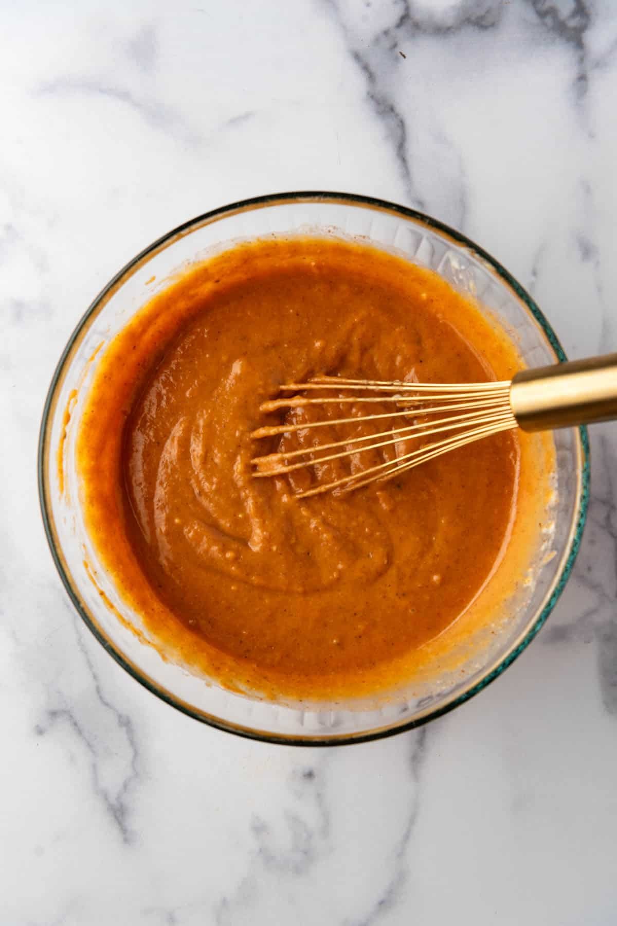 Whisked ingredients in a mixing bowl for sweet potato pie filling.