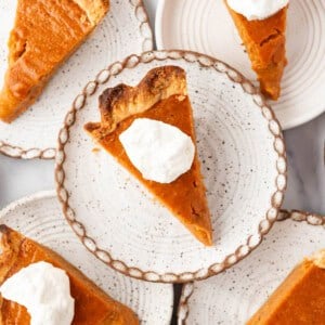 Slices of sweet potato pie on plates with whipped cream.