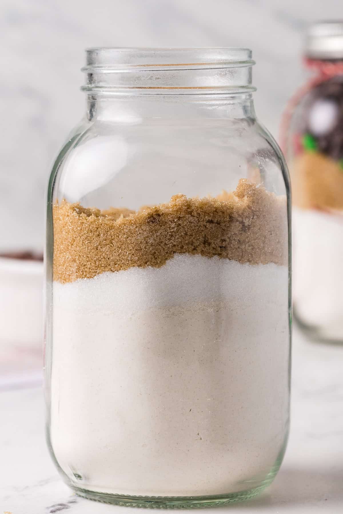 A layer of brown sugar and white sugar on top of a layer of brown sugar in a glass jar.