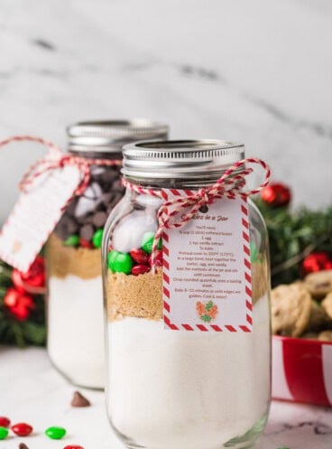Jars of cookie mix next to a plate of cookies and red & green M&Ms.