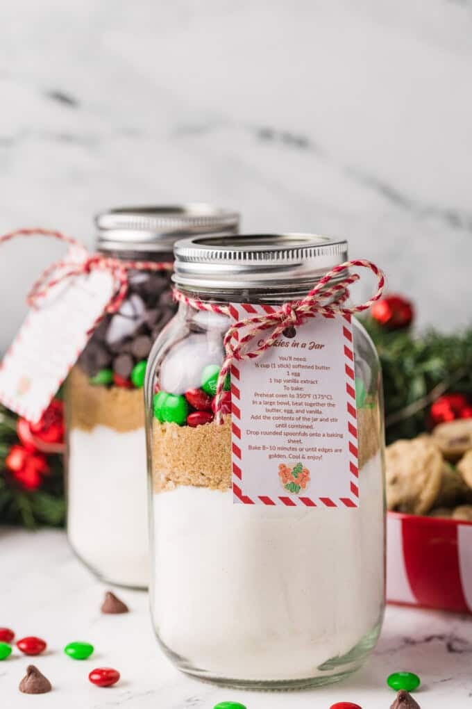 Jars of cookie mix next to a plate of cookies and red & green M&Ms.