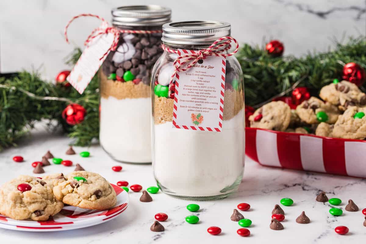Jars of cookie mix next to a plate of cookies and red & green M&Ms.