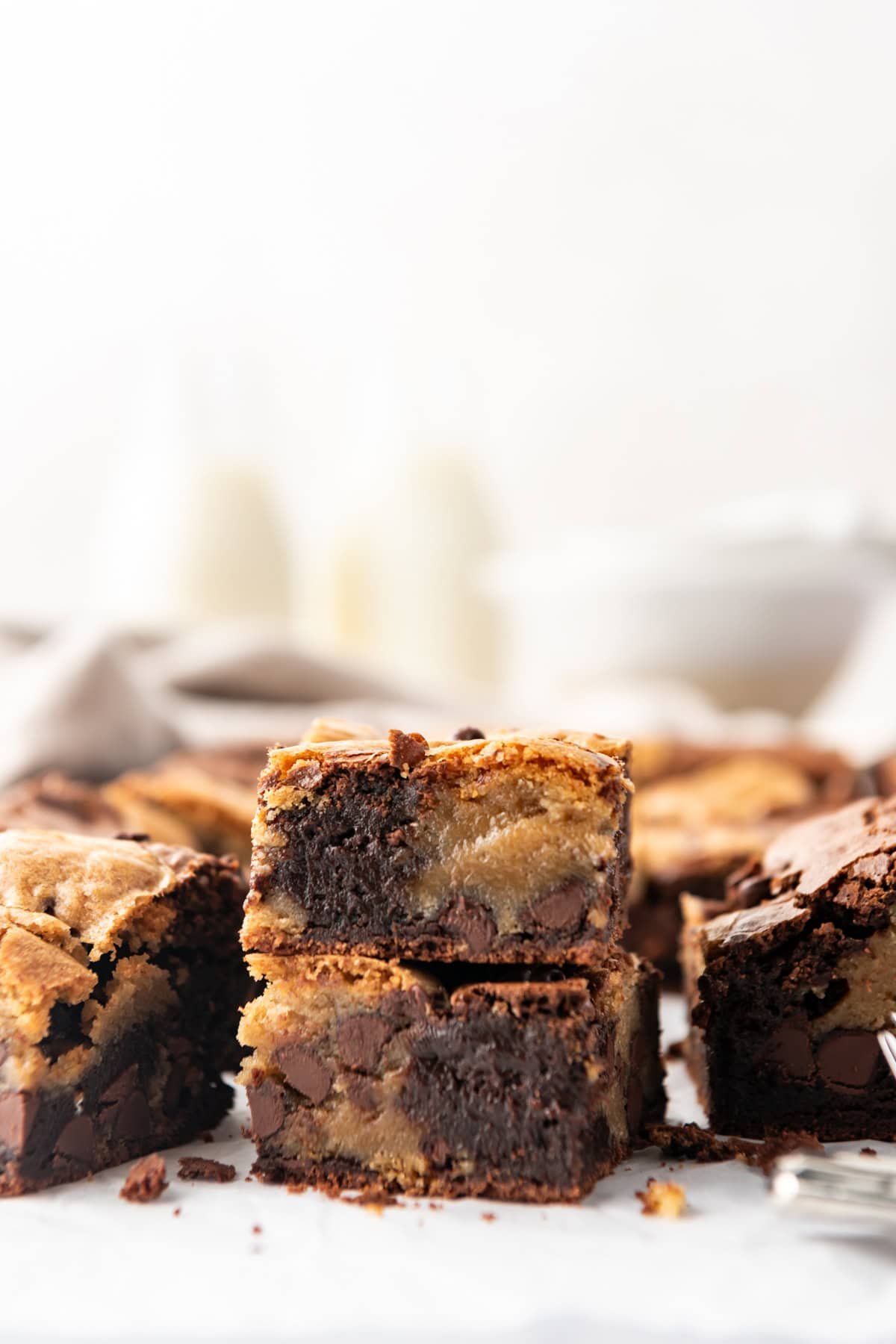 Stacked brookies with glasses of milk behind them.