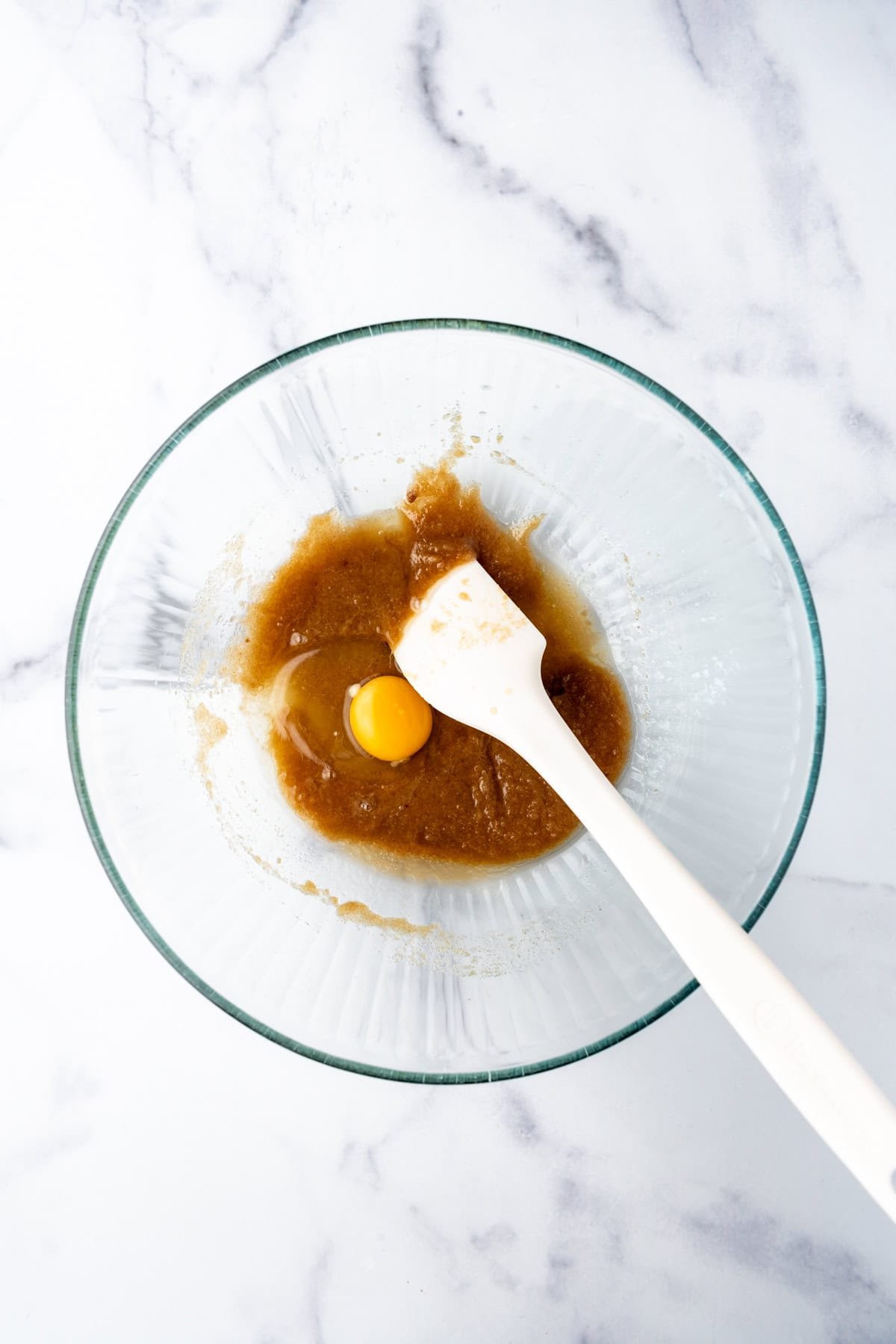 A white spatula in a bowl with melted butter and brown sugar.