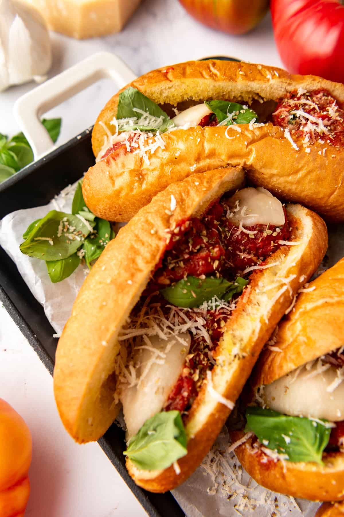 Italian meatball sub sandwiches with freshly grated parmesan cheese and fresh basil.