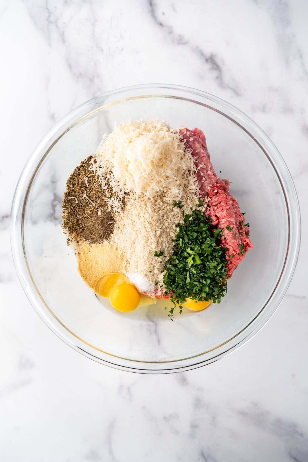 Combining ingredients in a large mixing bowl to make Italian meatballs.
