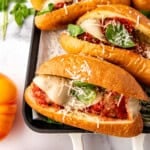 Homemade meatball subs with basil, garlic, tomatoes, and parmesan nearby.