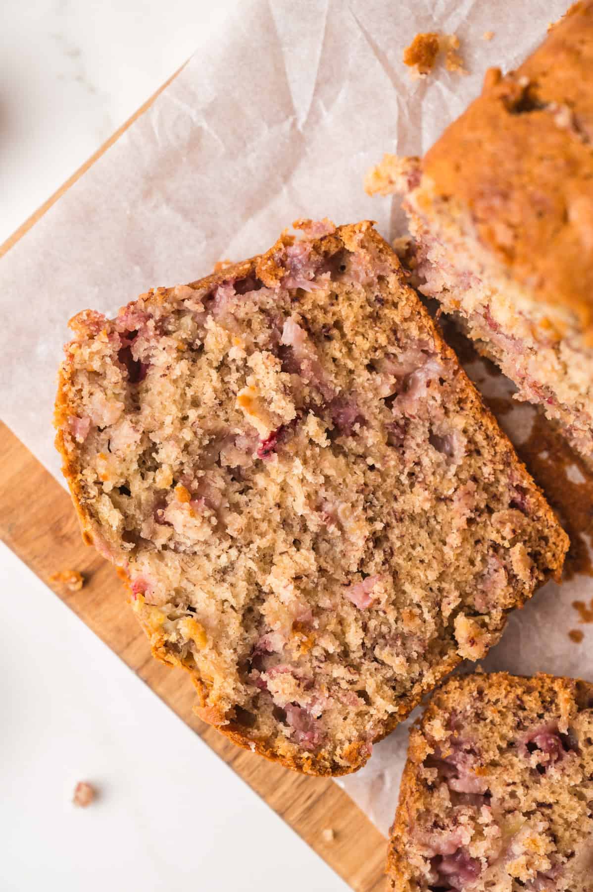 An overhead image of a slice of strawberry banana bread on white parchment paper.