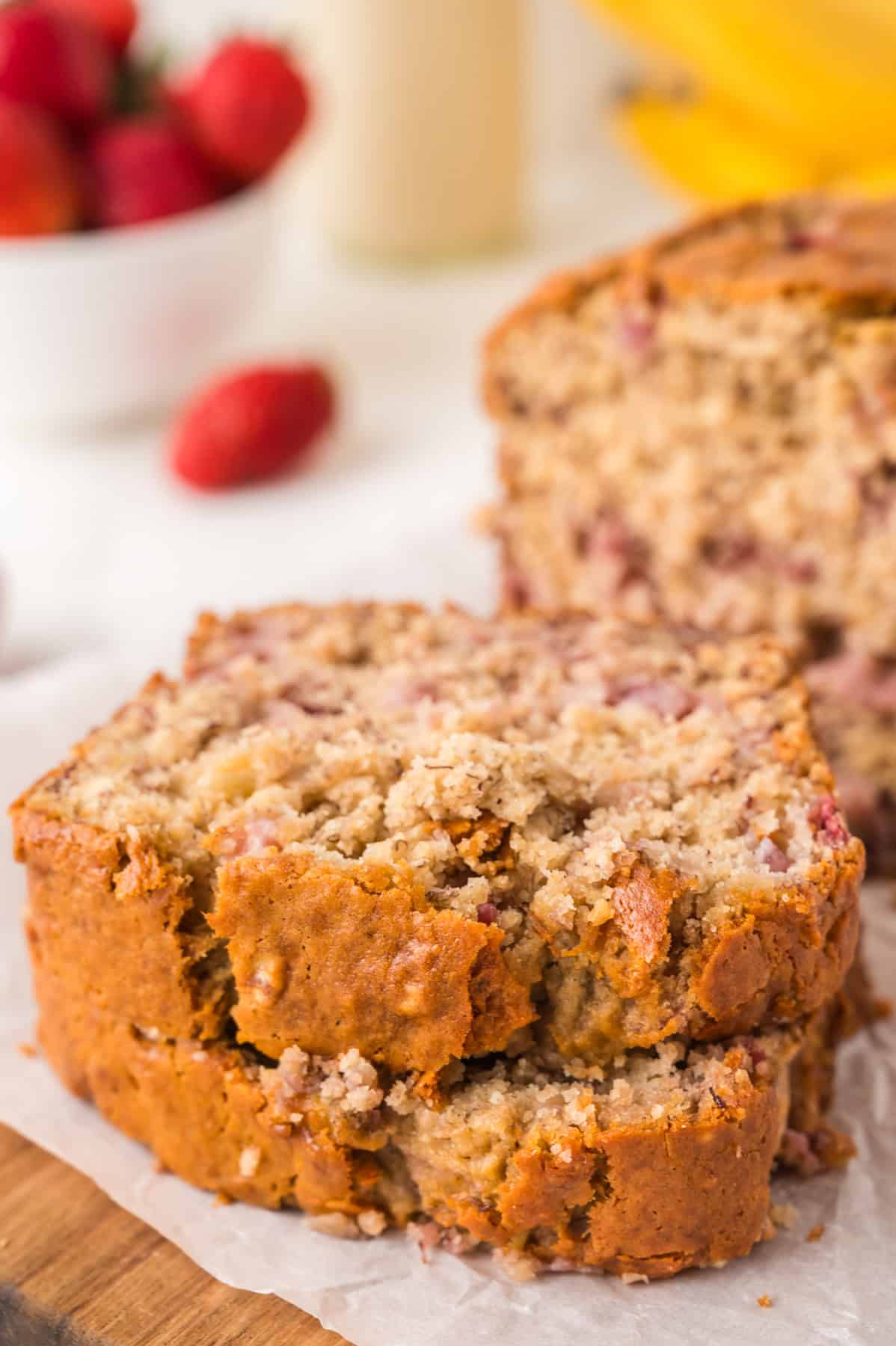 Stacked slices of banana bread with strawberries.
